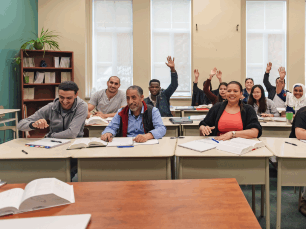 Adult learners raising hands in Skills Bootcamp class.